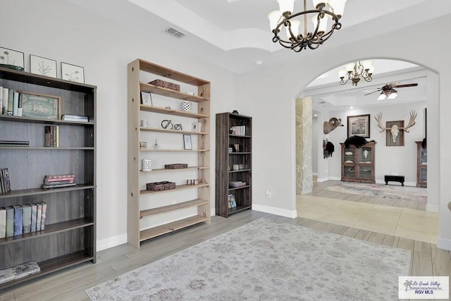 interior space with a notable chandelier, hardwood / wood-style flooring, and a raised ceiling