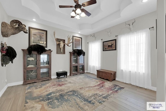 misc room with ceiling fan, a raised ceiling, and light hardwood / wood-style flooring