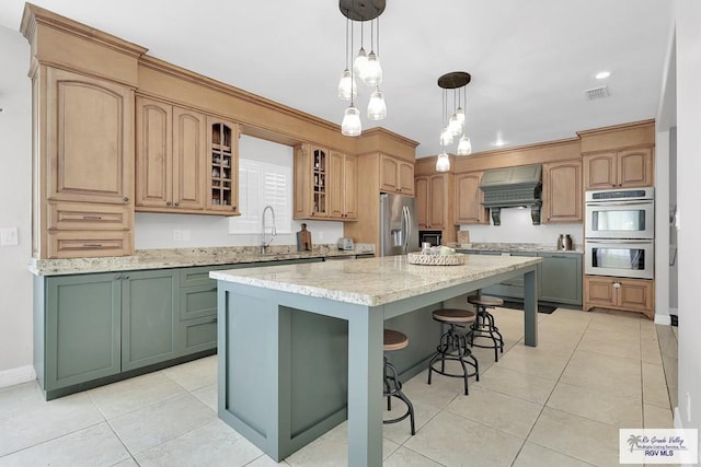 kitchen with premium range hood, appliances with stainless steel finishes, a center island, and light stone countertops