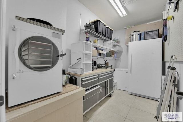 kitchen featuring washer / dryer, white fridge, and light tile patterned floors