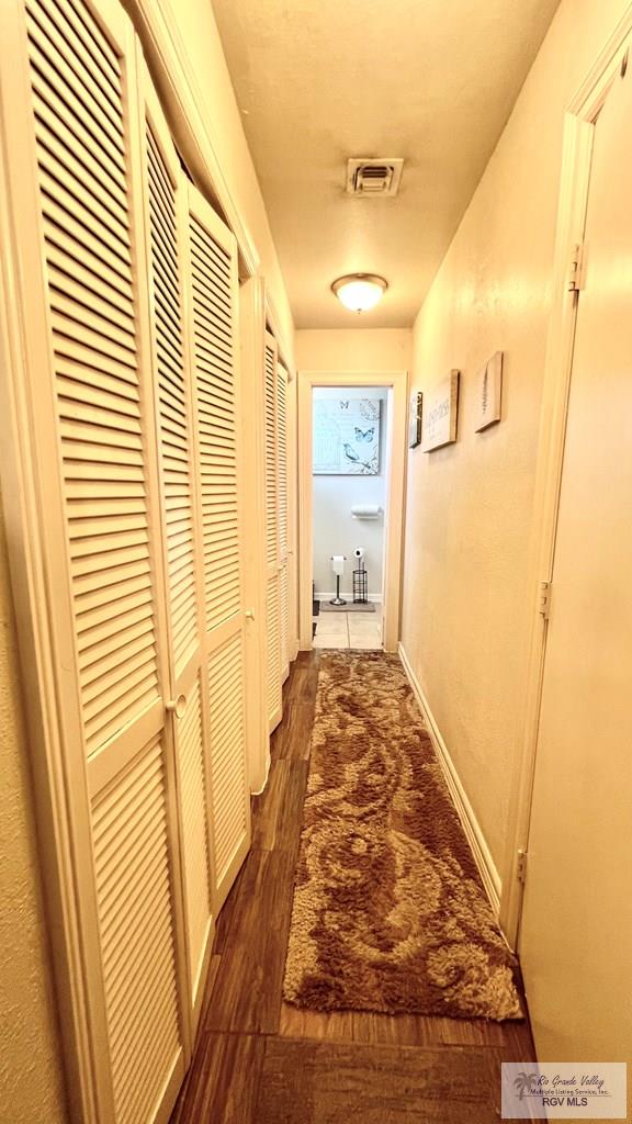 hallway featuring visible vents and dark wood-style flooring