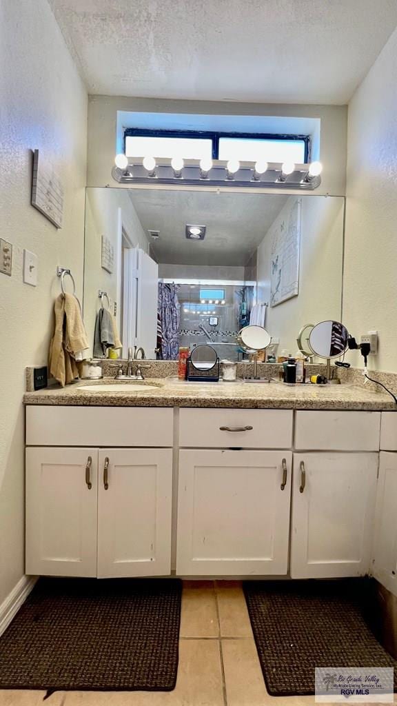 bathroom with a shower with curtain, tile patterned floors, double vanity, and a sink