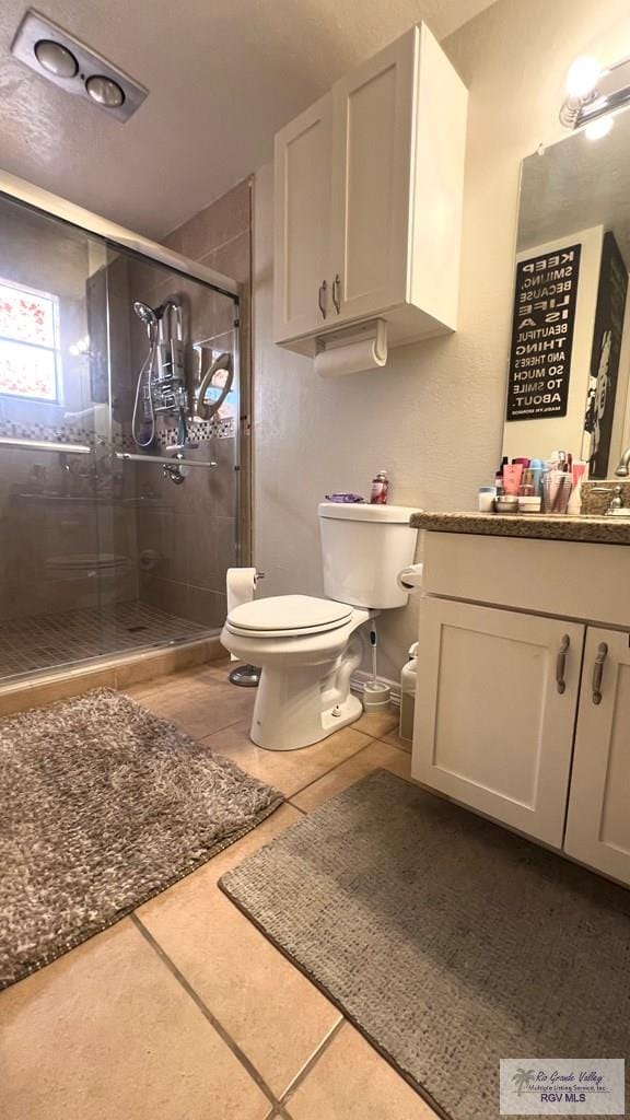 bathroom featuring a shower stall, tile patterned flooring, vanity, and toilet