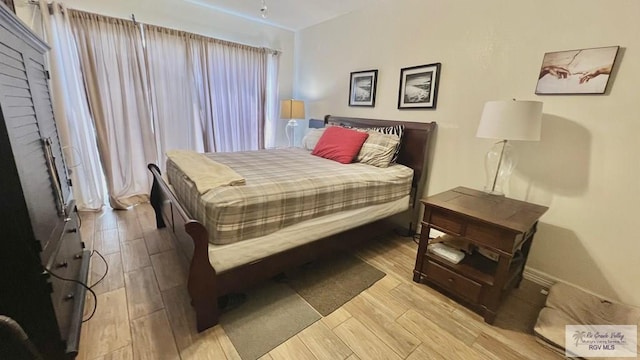 bedroom with wood finished floors, a brick fireplace, and baseboards