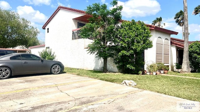 view of property exterior featuring stucco siding, a yard, and a tiled roof