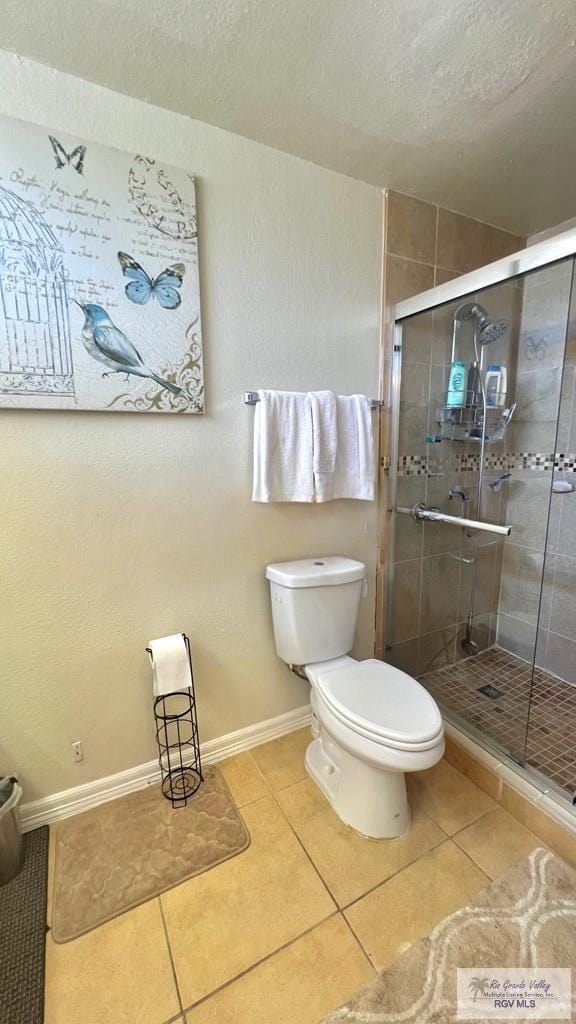 full bath with a shower stall, tile patterned flooring, toilet, baseboards, and a textured ceiling