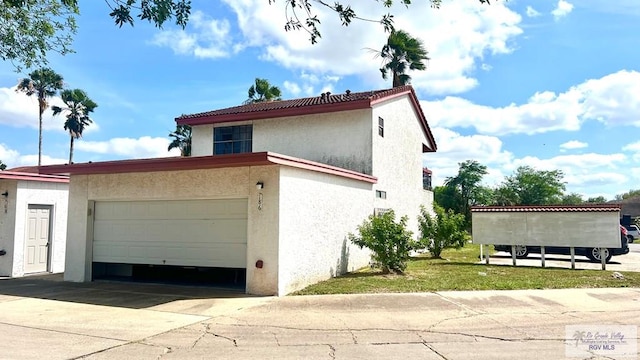 view of side of property with stucco siding, an attached garage, and concrete driveway