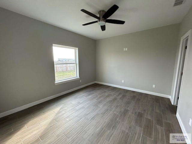 spare room with baseboards, visible vents, dark wood-style flooring, and ceiling fan