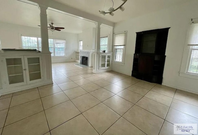 unfurnished living room with light tile patterned floors, a wealth of natural light, and ceiling fan