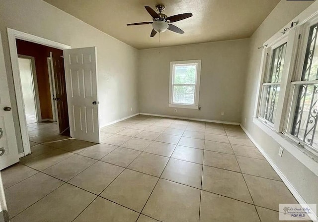 tiled spare room featuring ceiling fan