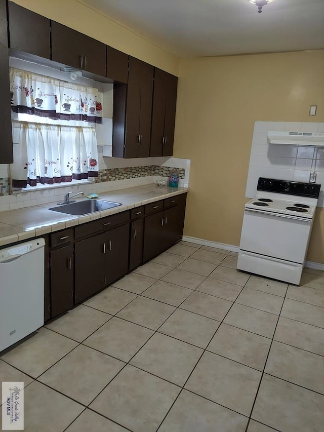 kitchen featuring dark brown cabinets, sink, white appliances, and backsplash