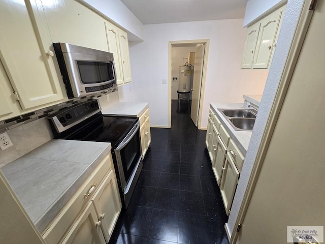 kitchen featuring stainless steel appliances, cream cabinets, sink, and water heater