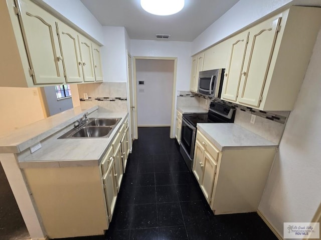 kitchen with backsplash, stainless steel appliances, sink, and cream cabinetry