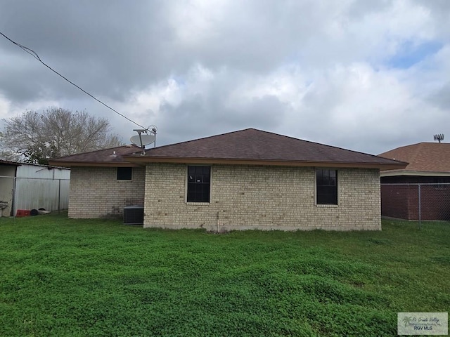 rear view of property featuring cooling unit and a lawn