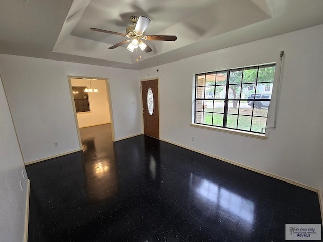 interior space featuring ceiling fan with notable chandelier and a raised ceiling