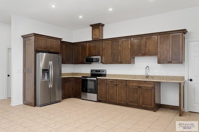 kitchen with dark brown cabinetry, light stone countertops, sink, and appliances with stainless steel finishes