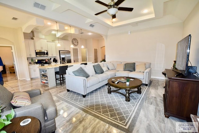 living room featuring a raised ceiling and ceiling fan