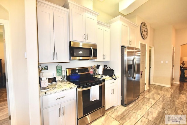 kitchen featuring stainless steel appliances, white cabinets, and light stone counters