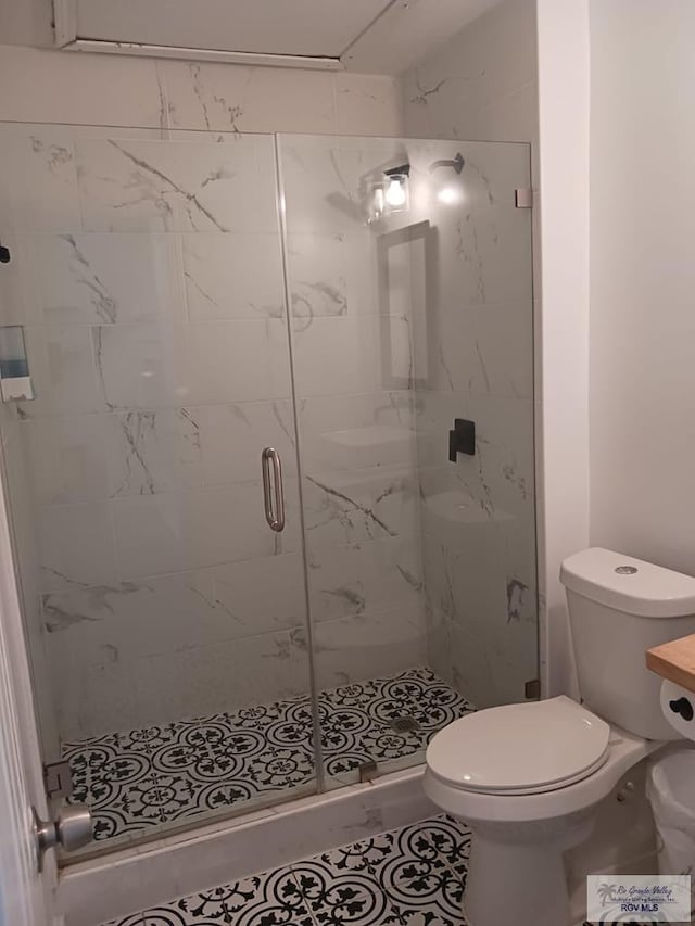 bathroom featuring tile patterned flooring, toilet, and walk in shower