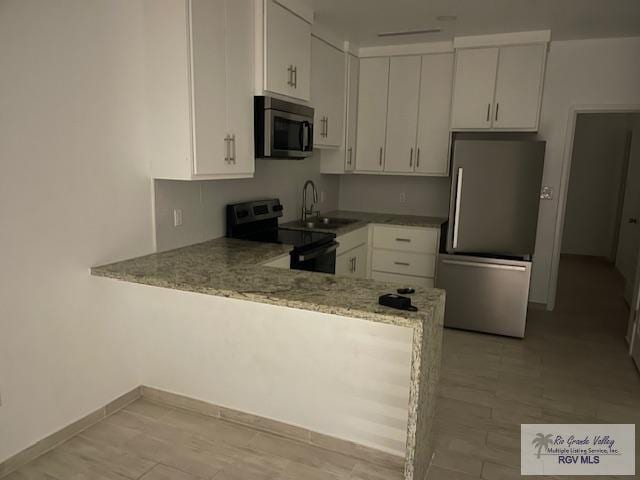 kitchen featuring kitchen peninsula, stainless steel appliances, white cabinetry, and sink