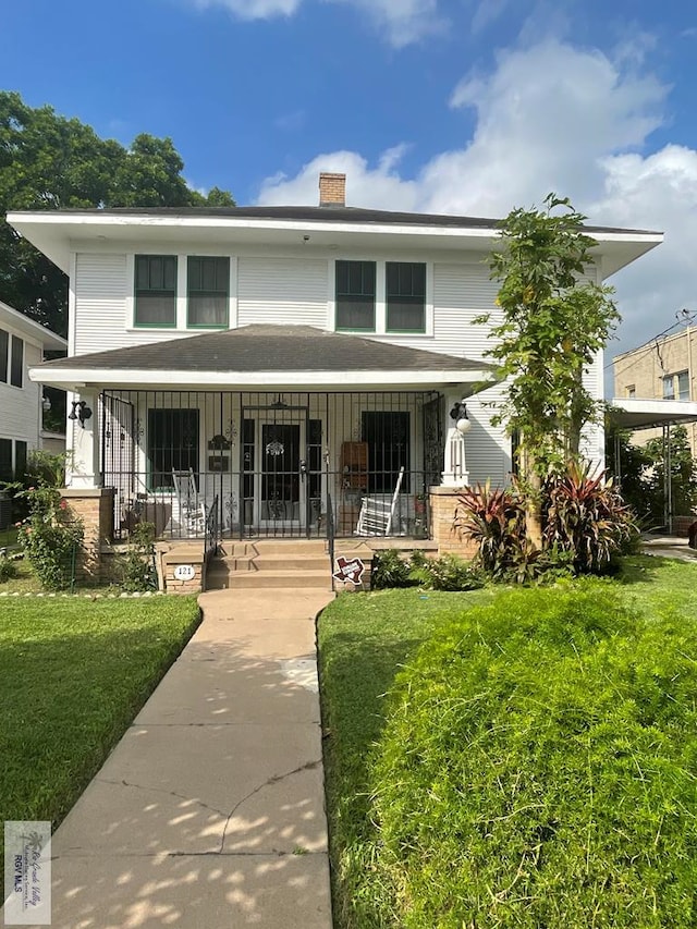 121 E Washington St, Brownsville, TX 78520 - traditional style home with covered porch, a front yard, and a chimney