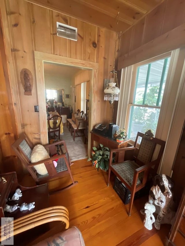 living area with wood walls and hardwood / wood-style flooring