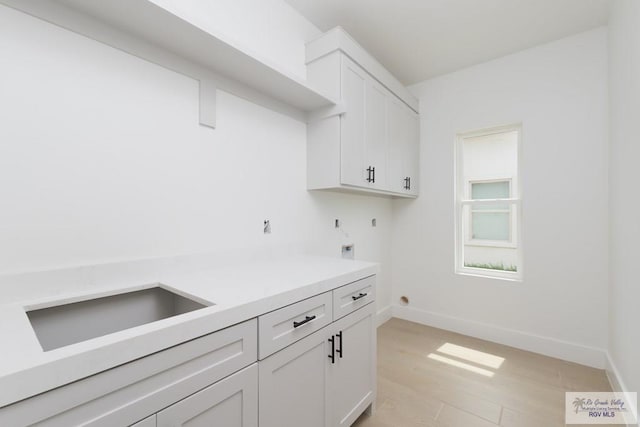 8830 Wentz Lk, Brownsville, TX 78520 - laundry area featuring hookup for an electric dryer, cabinet space, hookup for a washing machine, light wood-type flooring, and baseboards
