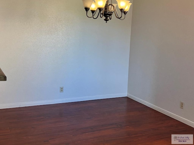 unfurnished room featuring a chandelier and dark hardwood / wood-style floors