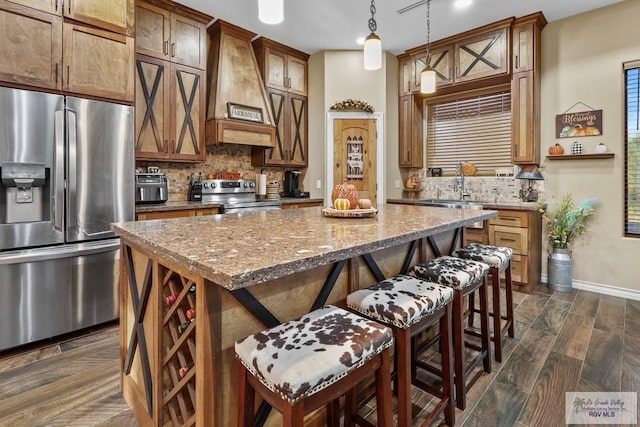 kitchen featuring a center island, premium range hood, sink, decorative light fixtures, and stainless steel appliances