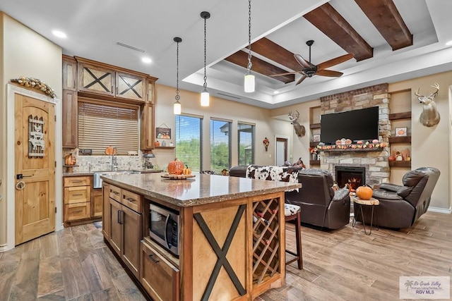 kitchen featuring sink, light stone counters, decorative light fixtures, a breakfast bar area, and a kitchen island