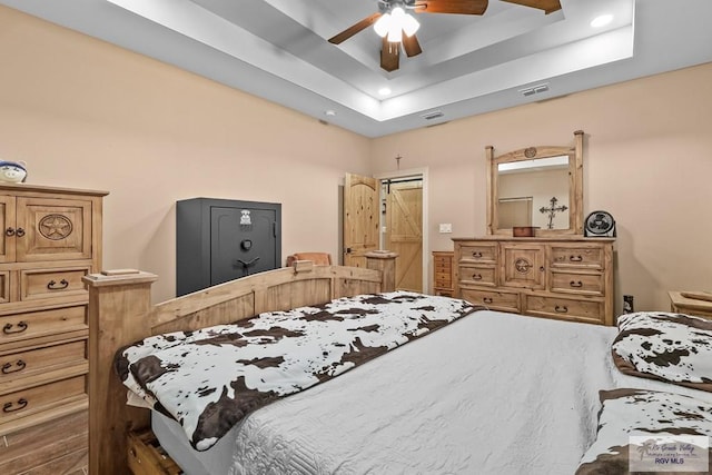 bedroom with ceiling fan and a tray ceiling