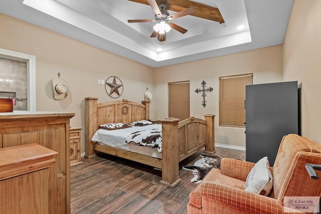 bedroom with dark hardwood / wood-style floors, a raised ceiling, and ceiling fan