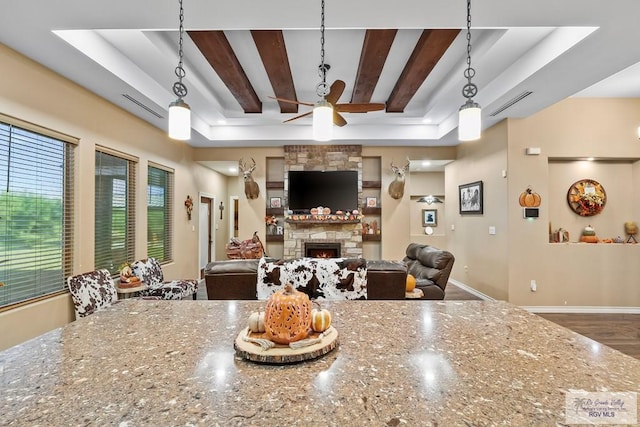 kitchen featuring a tray ceiling, light stone countertops, ceiling fan, and hanging light fixtures