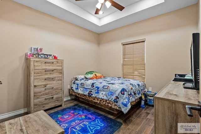 bedroom with a raised ceiling, ceiling fan, and dark wood-type flooring