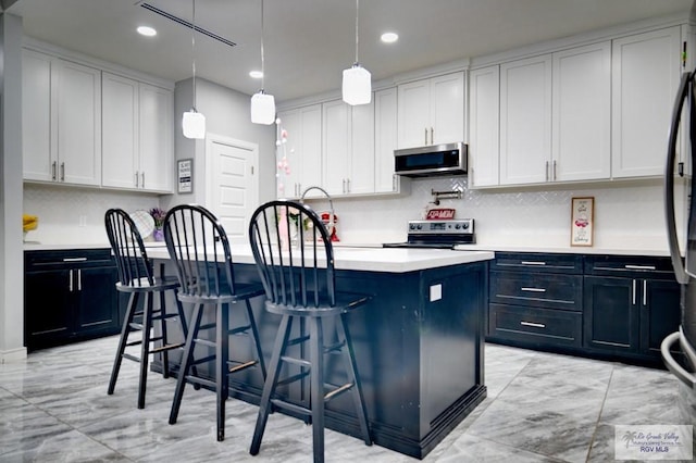 kitchen featuring a center island with sink, a sink, white cabinetry, appliances with stainless steel finishes, and light countertops