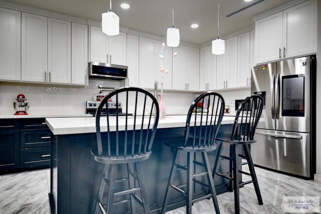 kitchen featuring light countertops, a center island with sink, backsplash, and stainless steel appliances