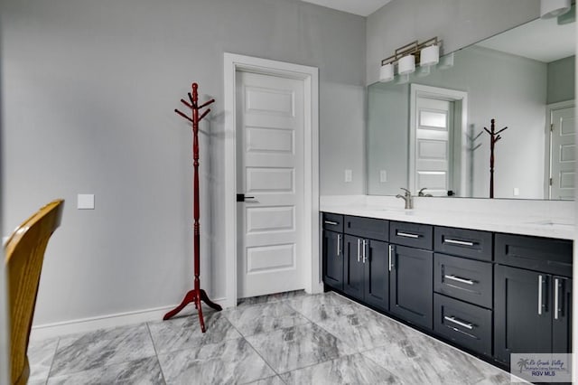 bathroom with double vanity, baseboards, and marble finish floor