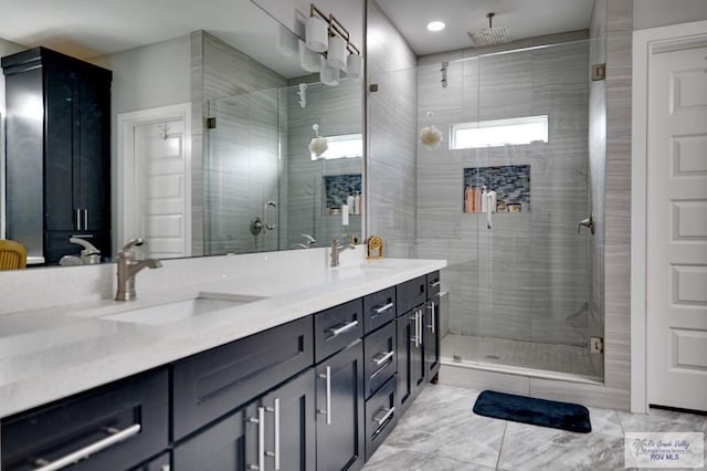 bathroom featuring double vanity, a stall shower, and a sink