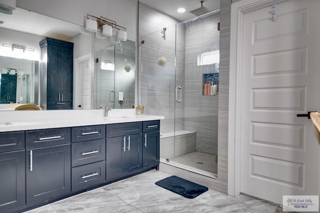 bathroom with a sink, a shower stall, and double vanity