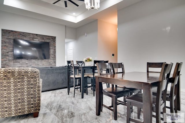 dining area featuring ceiling fan with notable chandelier and marble finish floor