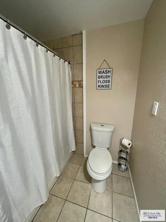 bathroom featuring tile patterned flooring, toilet, and walk in shower