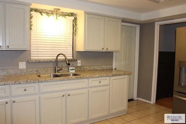 kitchen with light tile patterned flooring, white cabinets, and sink