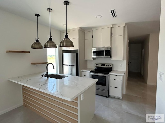 kitchen featuring sink, light stone countertops, appliances with stainless steel finishes, decorative light fixtures, and kitchen peninsula