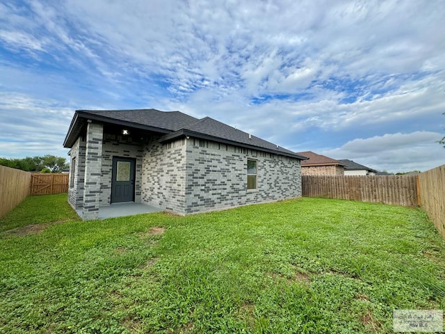 exterior space with brick siding, a lawn, and a fenced backyard