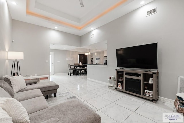 living room with a tray ceiling and a towering ceiling