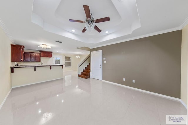 unfurnished living room with a raised ceiling, crown molding, ceiling fan, and light tile patterned flooring