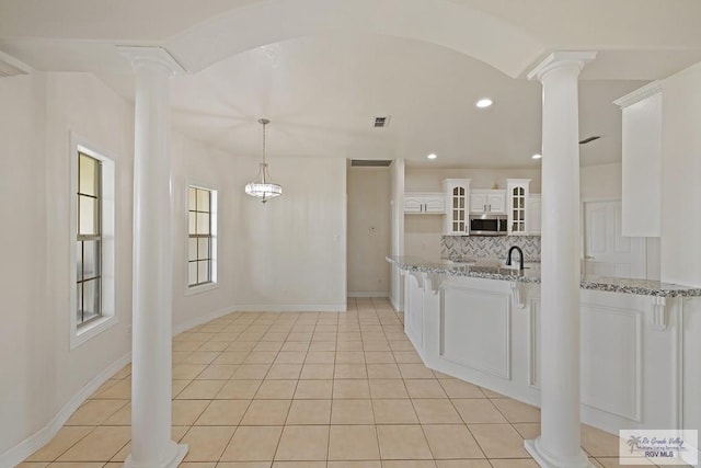 3271 Emerald Valley Blvd Unit 8, Brownsville, TX 78526 - kitchen with stainless steel microwave, ornate columns, tasteful backsplash, glass insert cabinets, and light stone counters