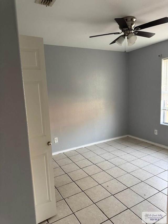 tiled spare room with ceiling fan