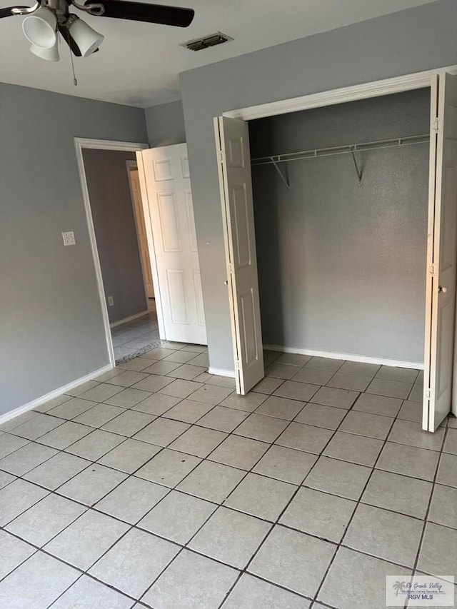 unfurnished bedroom with light tile patterned floors, a closet, and ceiling fan