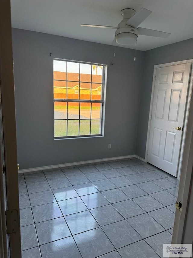 spare room with ceiling fan and light tile patterned floors